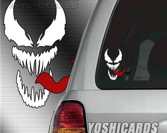 May include: A white vinyl decal featuring the stylized face of a creature with sharp teeth and a long red tongue, shown as a large graphic on the left and applied to the rear window of a silver vehicle on the right, with the text YOSHICARDS.