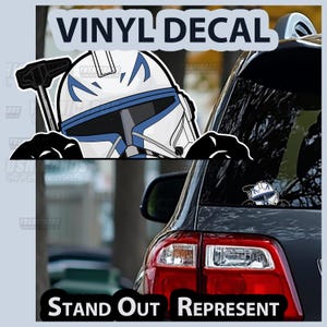 May include: A vinyl decal featuring a white and blue helmet design, with the text "VINYL DECAL" above and "STAND OUT REPRESENT" below. The decal is shown applied to a car window, with a smaller version of the helmet design visible.
