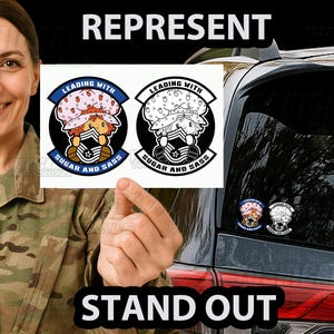 May include: Two circular stickers with a cartoon character wearing a strawberry hat and military uniform. The stickers have the text "LEADING WITH SUGAR AND SASS". The image also shows the words "REPRESENT" and "STAND OUT".