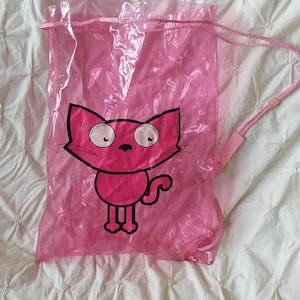 May include: A pink drawstring bag featuring a cartoon cat design. The cat is depicted in pink with a black outline. The bag is made of a translucent material and has pink drawstrings for closure.