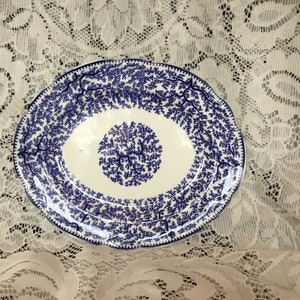 May include: A white oval serving platter with a blue floral pattern. The platter has a scalloped edge and a raised rim.