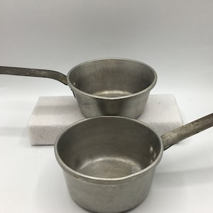 May include: Two silver aluminum camping pots with handles. The pots are nested together.