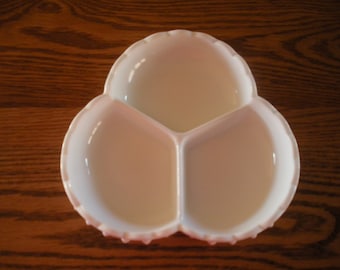 May include: A three-sectioned, off-white serving dish. The dish has a scalloped edge and is made of a glossy material. The three sections are divided by raised dividers. The dish is likely used for serving snacks or appetizers.