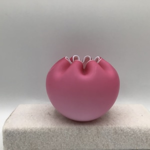 May include: A pink glass bowl with a white ruffled edge. The bowl is round and has a smooth, glossy finish.