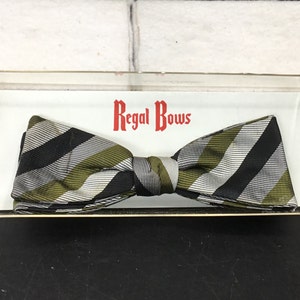 May include: A black, white, and green striped bow tie in a clear plastic box with the words "Regal Bows" printed on the label.