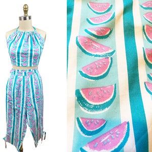 Può includere: Un completo in due pezzi con un top halter e pantaloni a gamba larga. Entrambi i pezzi sono realizzati in tessuto blu chiaro con una stampa di anguria bianca e rosa.