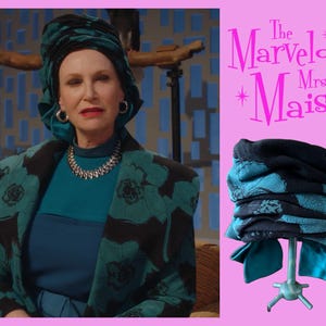 May include: A teal and black patterned fabric headwrap featuring a gathered, multi-layered design. The headwrap is displayed on a stand and is inspired by the style seen in The Marvelous Mrs. Maisel, showcasing a bold floral-like print.
