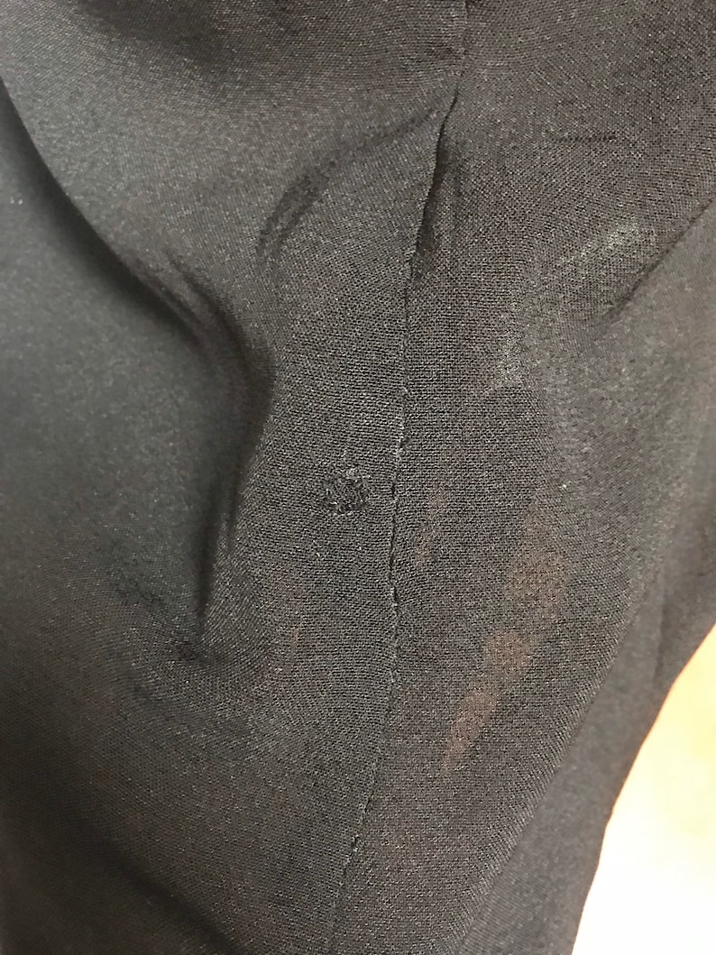 Pode incluir: Close-up de um tecido preto com uma costura que percorre o centro. O tecido tem uma superf&iacute;cie ligeiramente texturizada.