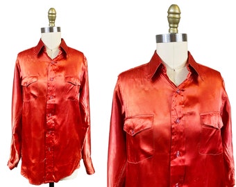 May include: A long-sleeved, red satin shirt with a button-down front and two chest pockets.