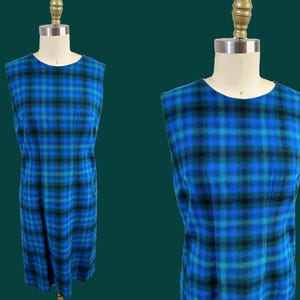 Op de afbeelding: Een mouwloze jurk met een blauw-zwart ruitpatroon. De jurk is aangesloten en heeft een rechte rok.