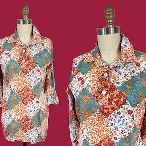 May include: A long-sleeved shirt with a patchwork design. The shirt features a collared neckline and three white buttons. The fabric is patterned with floral and geometric shapes in shades of orange, teal, red, and white.