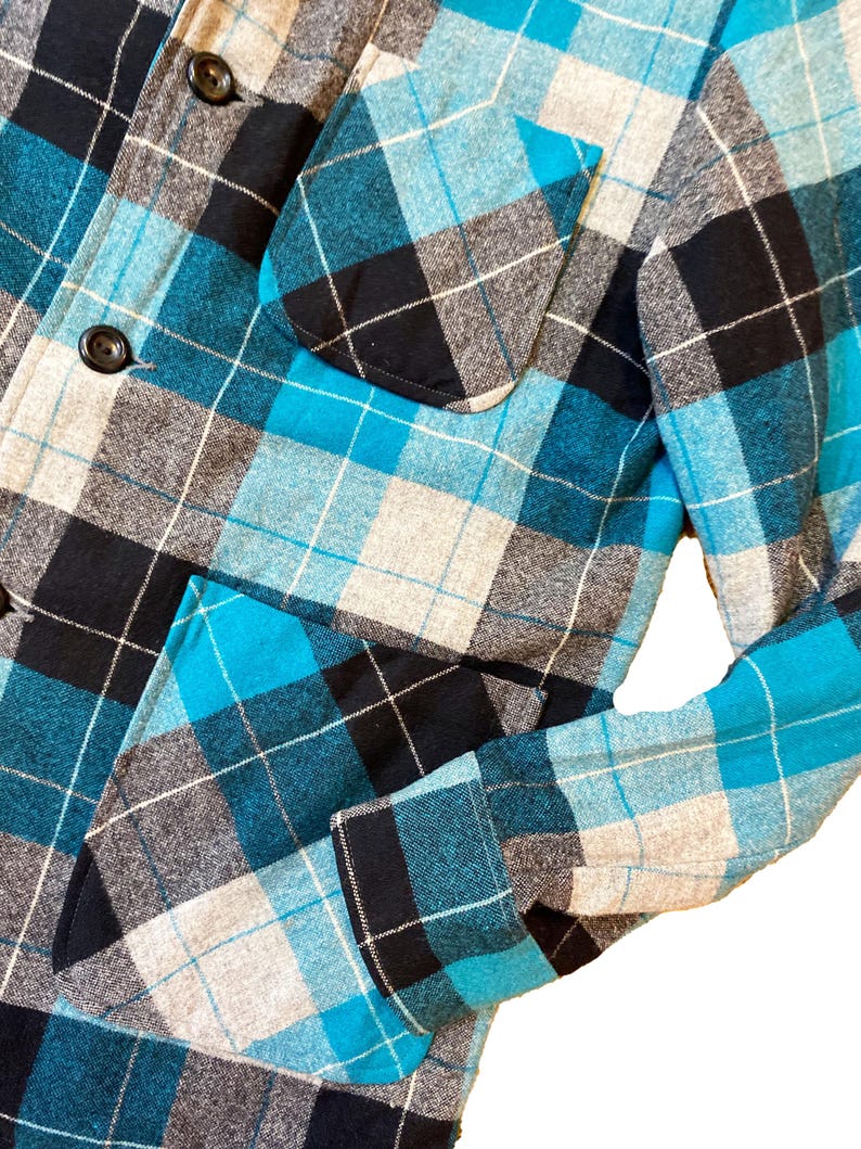 May include: A blue, black, and white plaid flannel shirt with a button-up front and two pockets.