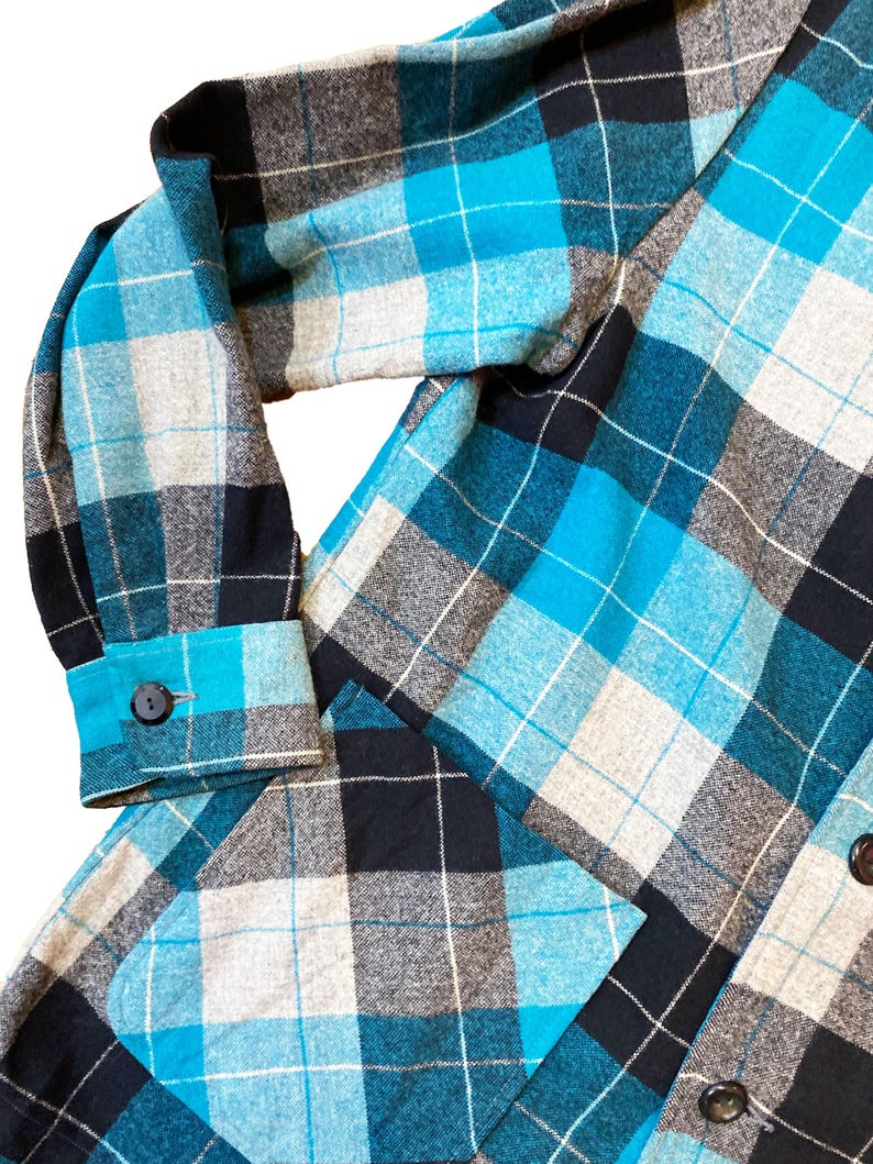 May include: A blue, black, and gray plaid flannel shirt with a patch pocket on the left side.