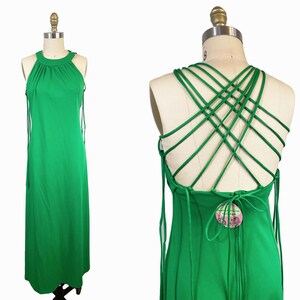 May include: A green maxi dress with a halter neckline and a criss-cross back design. The dress has thin straps that tie at the back.