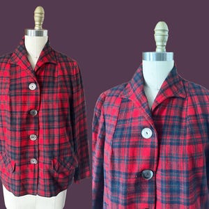May include: A red and black plaid jacket with a collared neckline and three large, round buttons. The jacket has two front pockets and is displayed on a mannequin. The plaid pattern is a classic design.