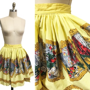 May include: A yellow cotton skirt with a gathered waist and a print of framed images of fruit and flowers. The skirt is a vintage style and would be perfect for a 1950s themed party.