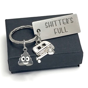 May include: A silver keychain with a silver tag that says "Shitter's Full" and two charms: a silver camper and a silver poop emoji with a smiley face.