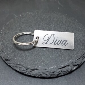 May include: Silver keychain with a rectangular tag that says "Diva" in a cursive font.