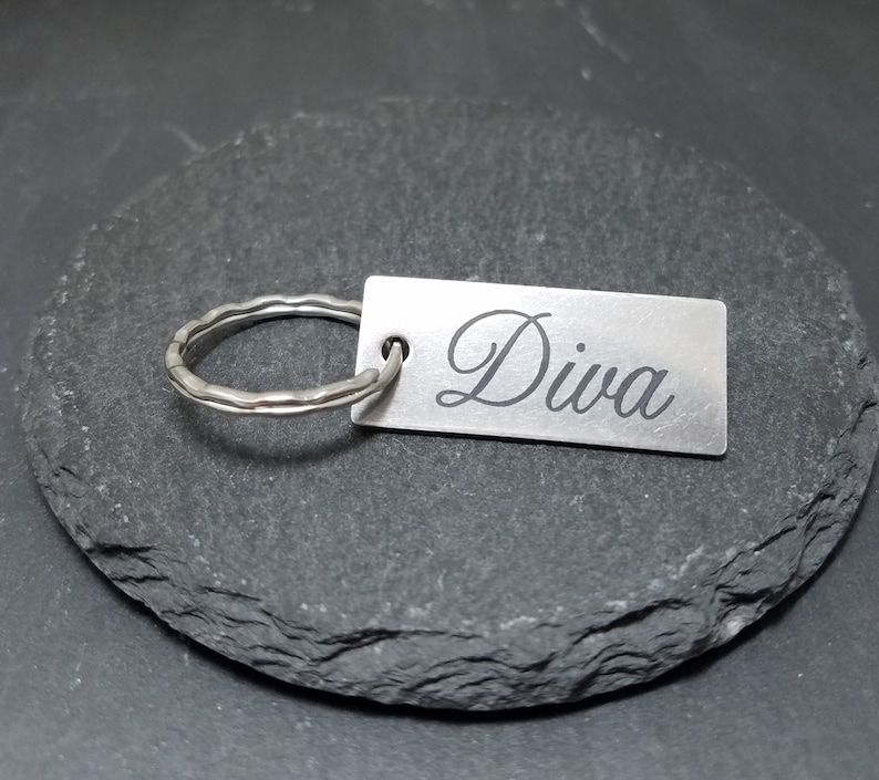 May include: Silver keychain with a rectangular tag that says "Diva" in a cursive font.