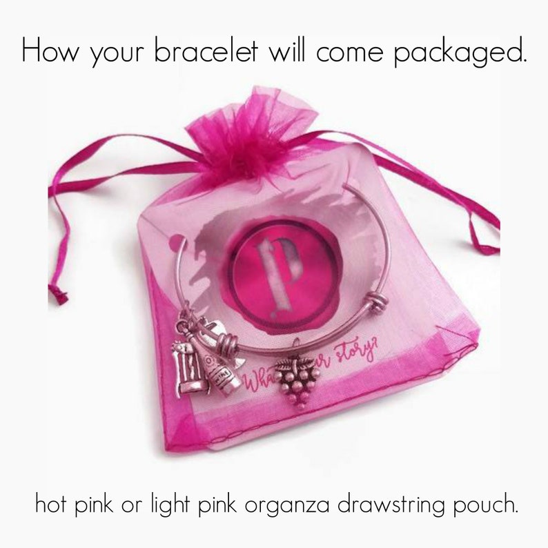 May include: A silver bracelet with a charm of a wine bottle and grapes comes packaged in a hot pink or light pink organza drawstring pouch. The pouch has a pink label with the text "What's your story?"