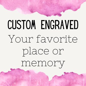 Puede incluir: Texto grabado personalizado sobre un fondo blanco con un borde de acuarela rosa. El texto dice "CUSTOM ENGRAVED Your favorite place or memory".
