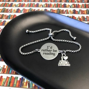 May include: A silver bracelet with a charm that says "I'd rather be reading" and a charm of stacked books with a heart on top that says "I love to read".