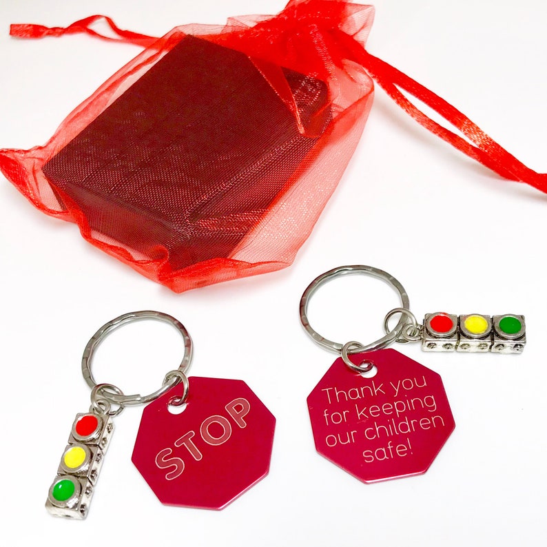 May include: Two red stop sign keychain charms with a silver key ring and a traffic light charm. The charms say "STOP" and "Thank you for keeping our children safe!"