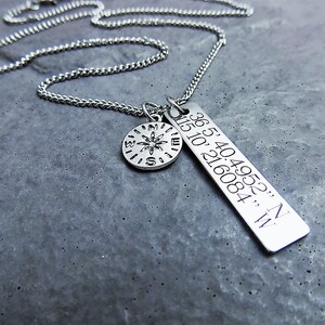 Puede incluir: Un collar de plata con un dije de br&uacute;jula y un dije rectangular con las coordenadas "36.54049523, N 115.10216084, W" grabadas en &eacute;l.
