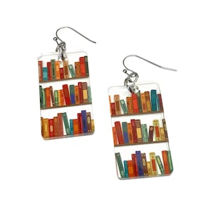 May include: A pair of clear acrylic earrings with a bookshelf design featuring colorful books. The earrings have silver hooks.