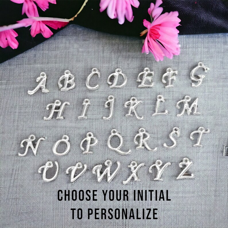 May include: Silver alphabet charms with cursive lettering. The charms are arranged in alphabetical order from A to Z. The text below the charms reads "Choose your initial to personalize".