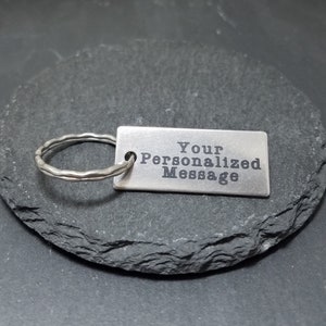 May include: Silver keychain with a rectangular tag that says "Your Personalized Message".