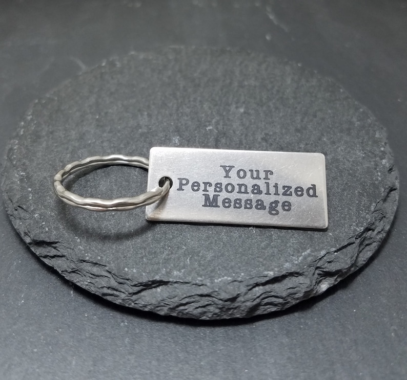 May include: Silver keychain with a rectangular tag that says "Your Personalized Message".