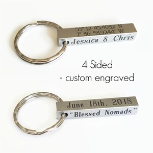 May include: A silver keychain with a rectangular metal tag engraved with the coordinates 55° 12' 45.4032 N 7° 36' 53.9244" W, the names "Jessica & Chris", the date "June 18th, 2018", and the phrase "Blessed Nomads".