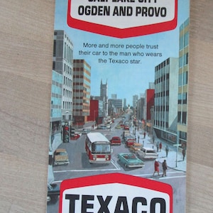 May include: A vintage Texaco advertisement featuring a city scene with buildings, cars, and a bus. The text reads "Salt Lake City Ogden and Provo" and "More and more people trust their car to the man who wears the Texaco star." The Texaco logo is prominently displayed at the bottom of the image.