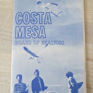 May include: A vintage blue and white brochure for Newport Harbor and Costa Mesa, featuring a sky with seagulls and three people looking up. The text reads "Board of Realtors".