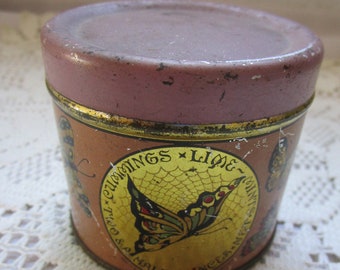 May include: A vintage metal tin with a pink lid and a yellow label. The label features a butterfly with a spiderweb design and the text "Cummings Lime Mints Two & a Half Ounces Net".