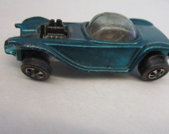 May include: Teal-colored vintage toy car with a clear bubble top and black wheels. The toy car has a detailed engine and a sleek, aerodynamic design. This collectible toy car is a classic.