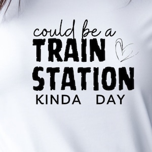 May include: White t-shirt with black text that reads "could be a train station kinda day" with a small heart drawn next to the word "train".