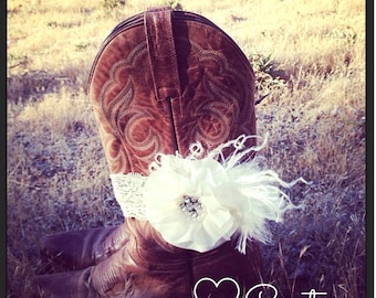 May include: A brown leather cowboy boot with a white lace and flower embellishment around the top. The boot is sitting on a bed of dry grass. The text "Couture" is written in white on a black heart.