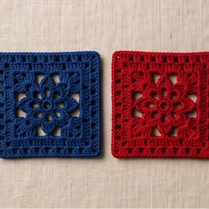 May include: Two square crochet coasters featuring a central floral motif with openwork detailing. One coaster is deep blue and the other is vibrant red, both crafted with a consistent yarn texture and a repeating geometric border pattern.
