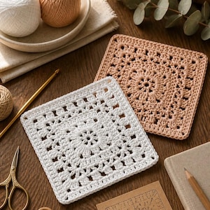 May include: A collection of crochet items on a wooden surface. Two crocheted squares, one white and one beige, are visible. Other items include balls of yarn, a crochet hook, scissors, buttons, a tape measure, and a pattern.