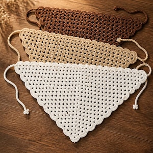 May include: Three handmade crochet bandanas in brown, beige, and white. Each bandana has a triangular shape with a scalloped edge and ties at the ends. The bandanas are displayed on a wooden surface.
