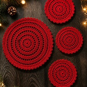 May include: A set of four circular red crochet doilies featuring intricate concentric patterns and scalloped edges. The collection includes one large doily and three smaller doilies, all crafted with a consistent vibrant red yarn.