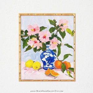 May include: A painting of a blue and white porcelain vase filled with pink hibiscus flowers. The vase is sitting on a table with lemons and oranges.