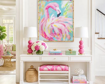May include: A rectangular wall art piece featuring a pink flamingo painting in a gold bamboo-style frame, displayed above a white console table with two pink spherical lamps, a floral arrangement, and a pink upholstered bench with white legs.