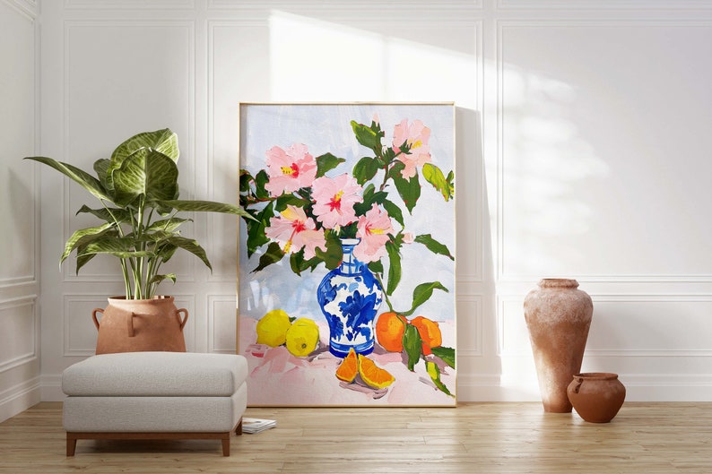 May include: A painting of a still life featuring a blue and white porcelain vase filled with pink hibiscus flowers, lemons, and oranges on a pink tablecloth.