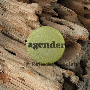 May include: A green button with the word "agender" printed in black letters.