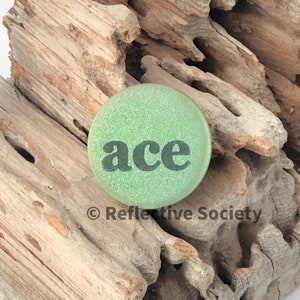 May include: A green button with the word "ace" printed in black letters.