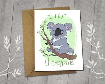 May include: A greeting card with a cartoon koala bear sitting on a branch. The card has the text "I love U-CALYPTUS" on it. The card is 5x6.5 inches and comes with a 5x7 inch envelope.