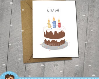 May include: A birthday card with a white background and a brown cake with three lit candles. The text "BLOW ME!" is printed in black at the top of the card.